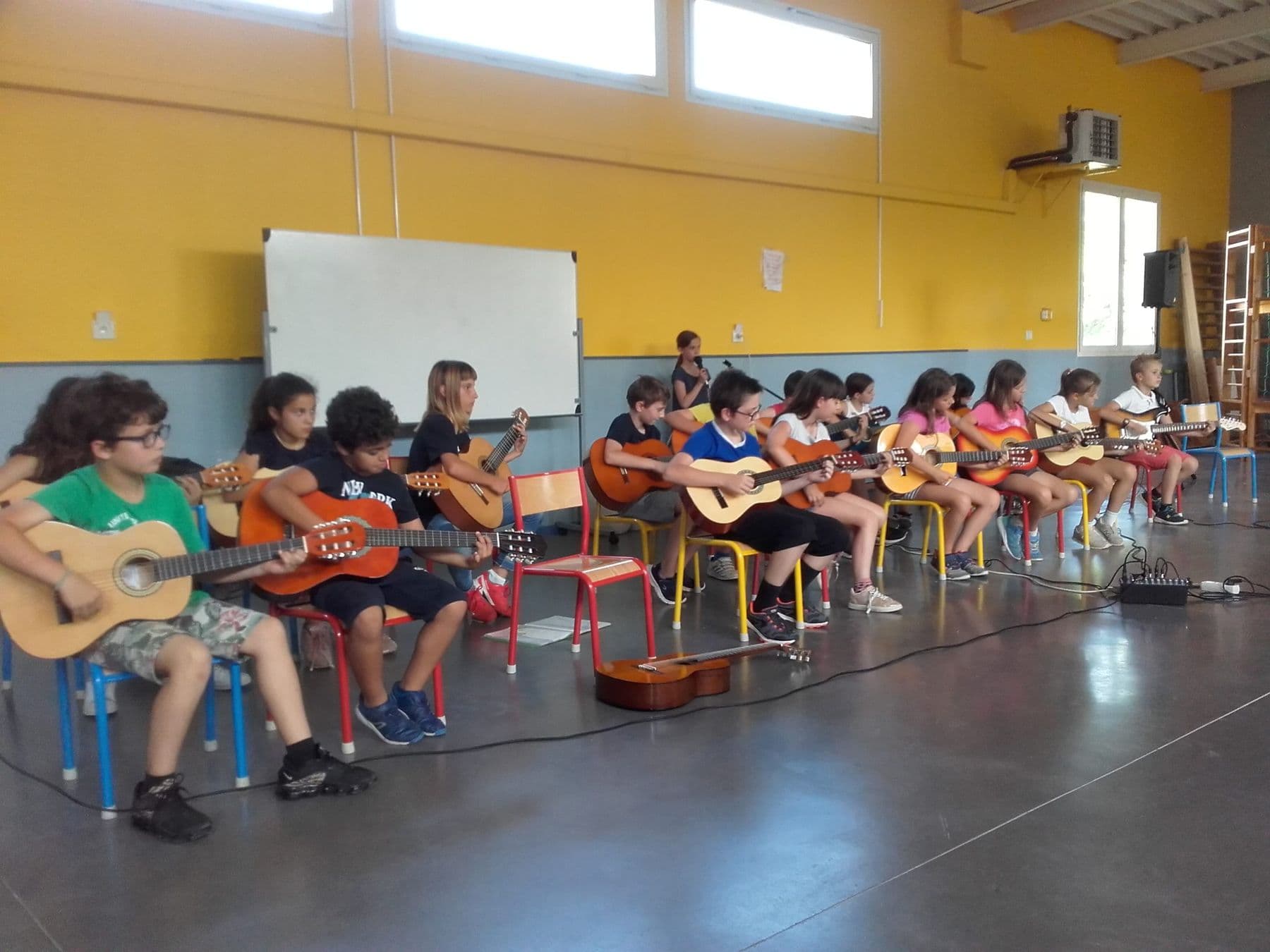 Une rangée d'élèves joue de la guitare au gymnase, lors d'une audition.
