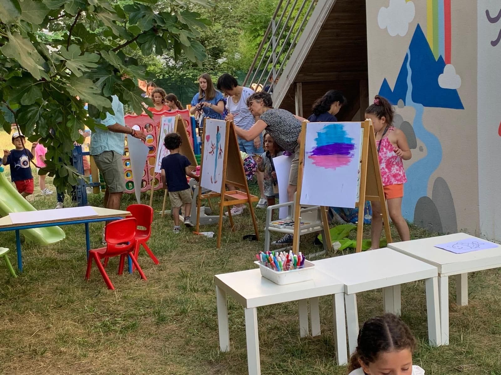 Atelier de peinture en plein air : des enfants peignent sur des chevalets dans le jardin.