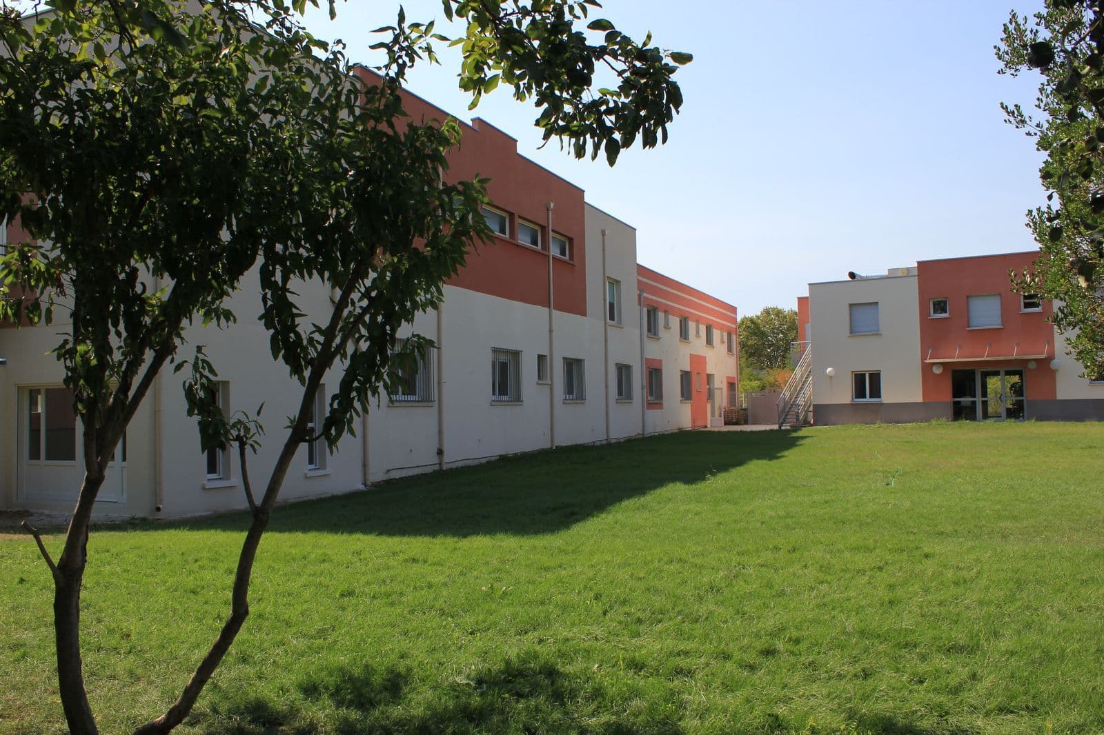 Les bâtiments de l'école bordant une grande pelouse ensoleillée.