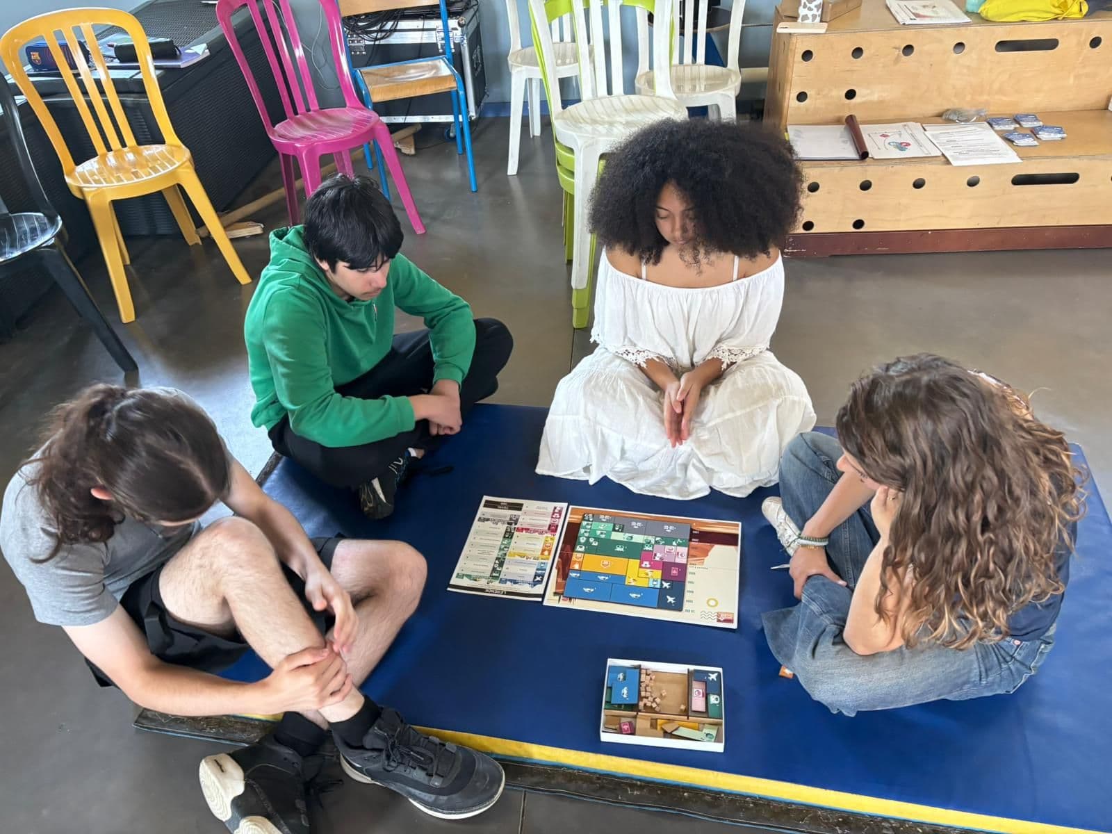 Middle school pupils sitting on mats play a board game.