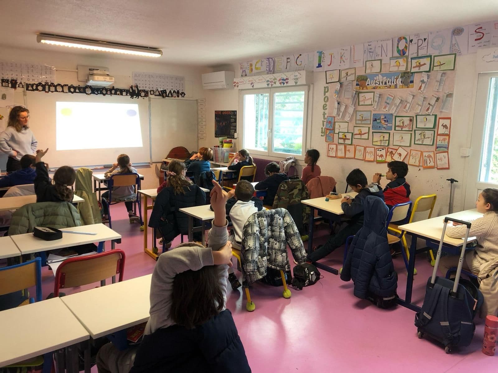 Une classe de primaire aux murs couverts de travaux d'élèves.