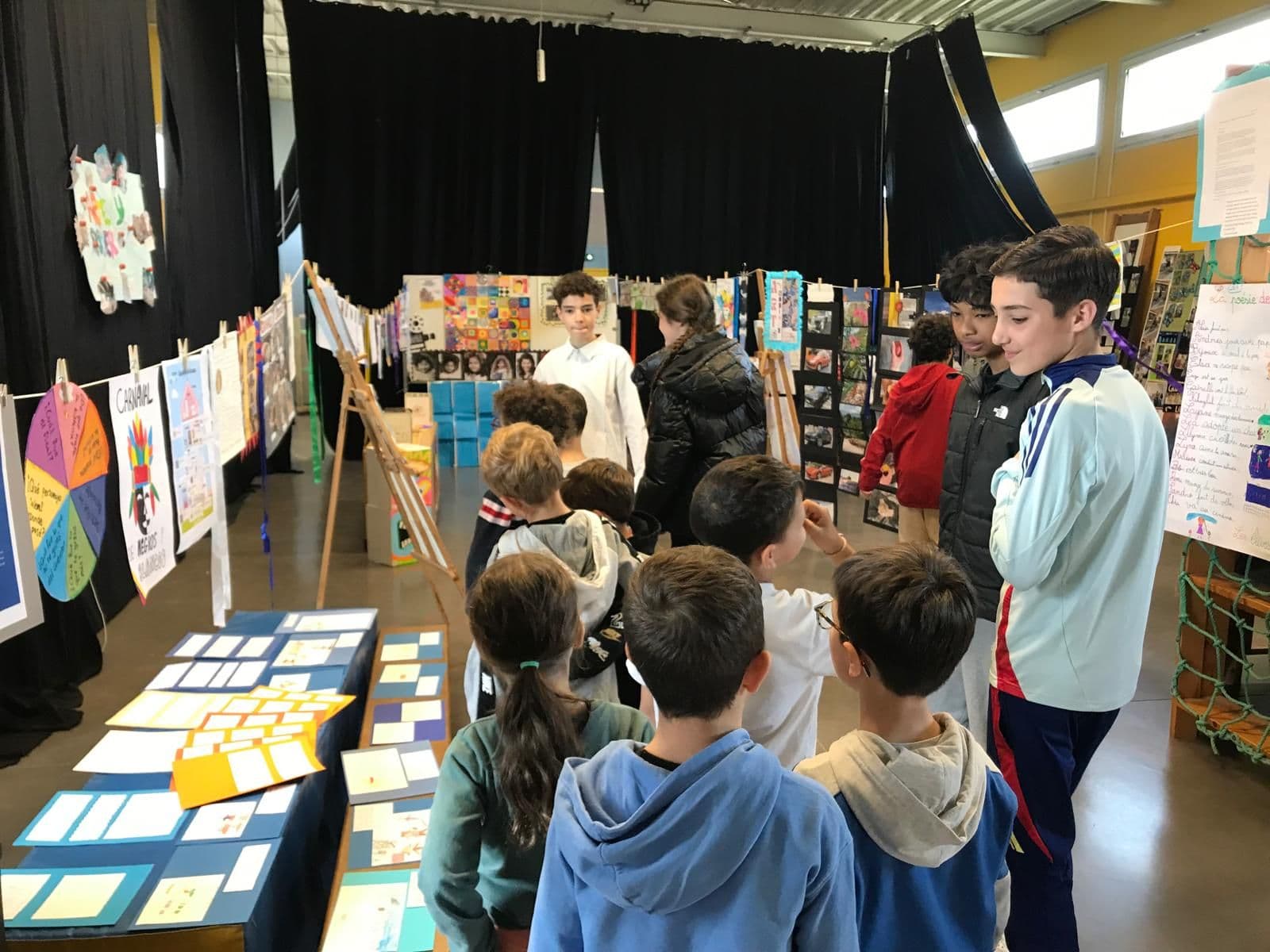 Alumnos visitan la exposición de trabajos de clase en la sala polivalente.