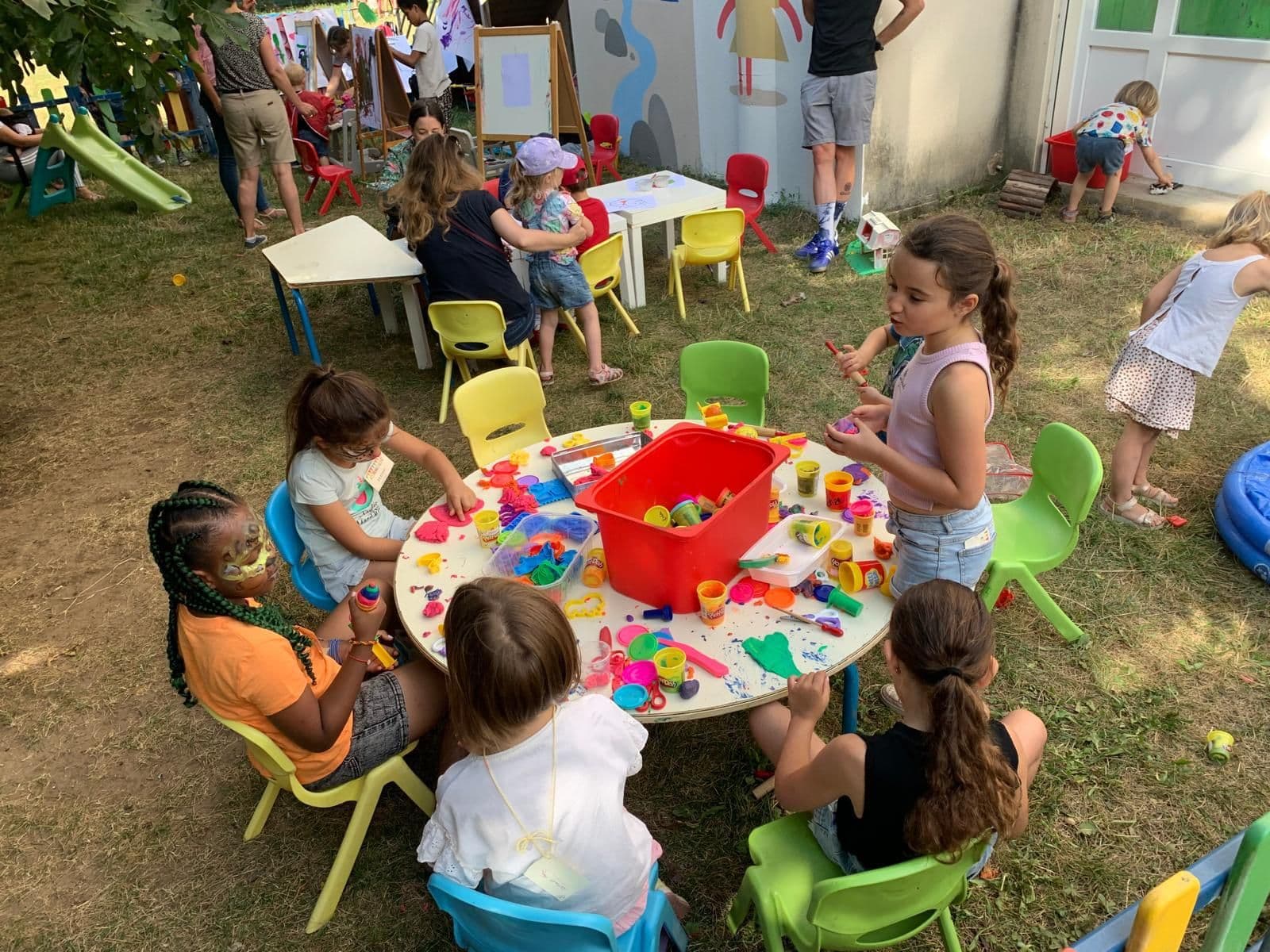 Atelier pâte à modeler sur la pelouse pendant la kermesse.