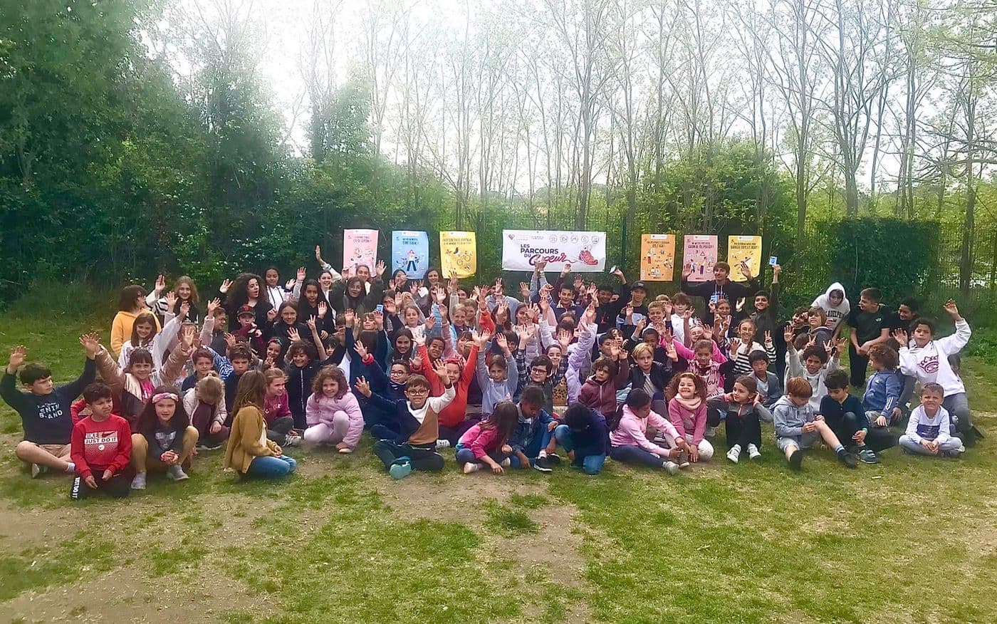 Pupils gathered on the lawn, arms raised, for the Parcours du Coeur health day.
