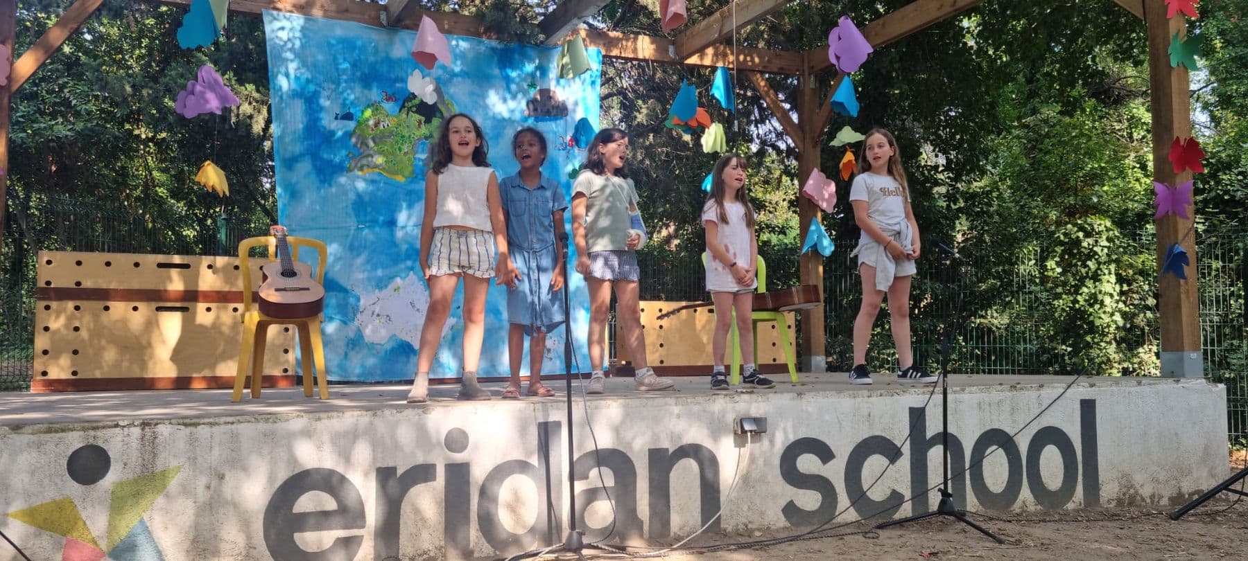 Pupils sing on the outdoor stage, marked Eridan School.
