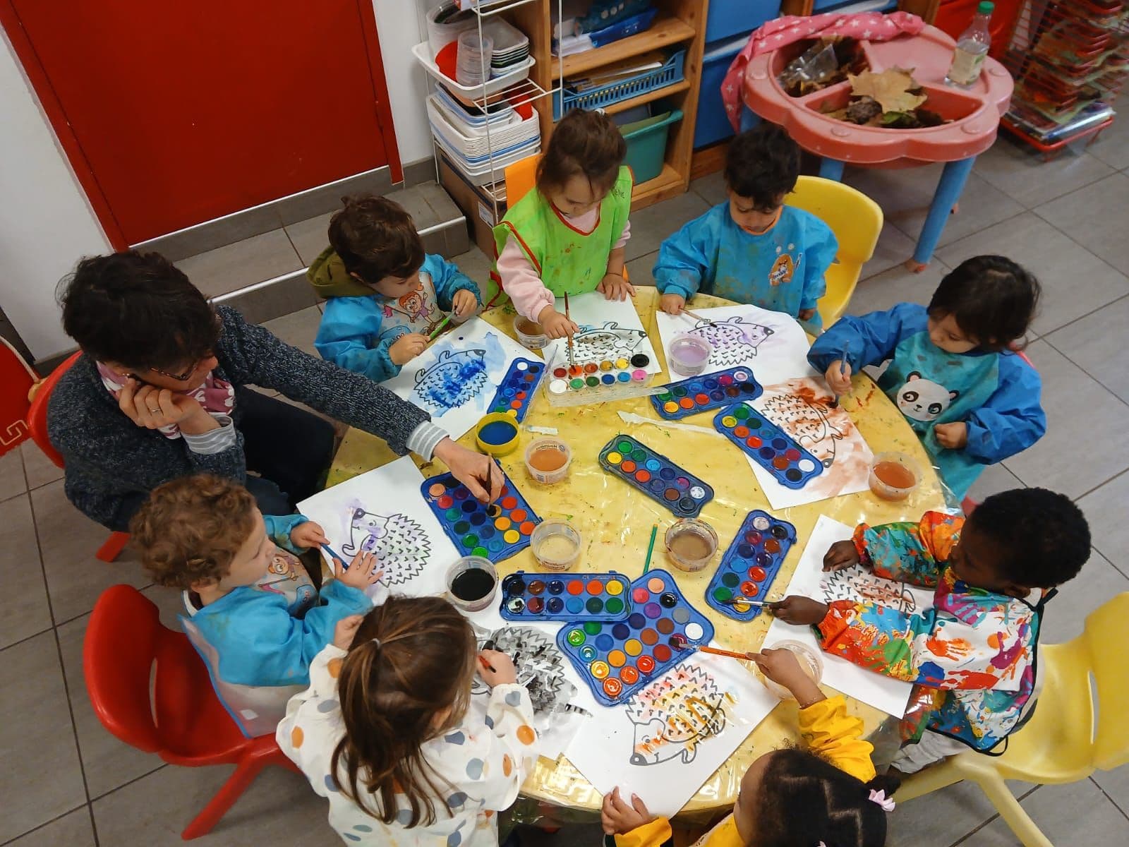 A watercolour workshop in pre-school, seen from above around a round table.