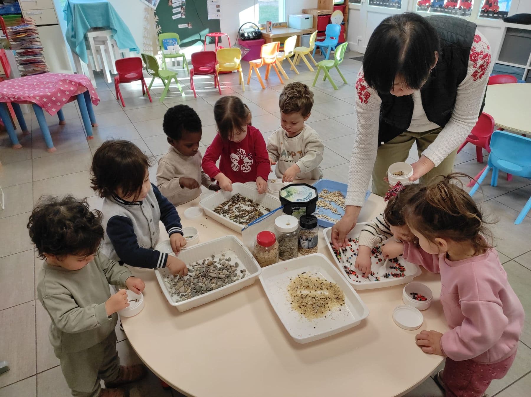 Actividad sensorial en infantil: los niños manipulan semillas en bandejas.