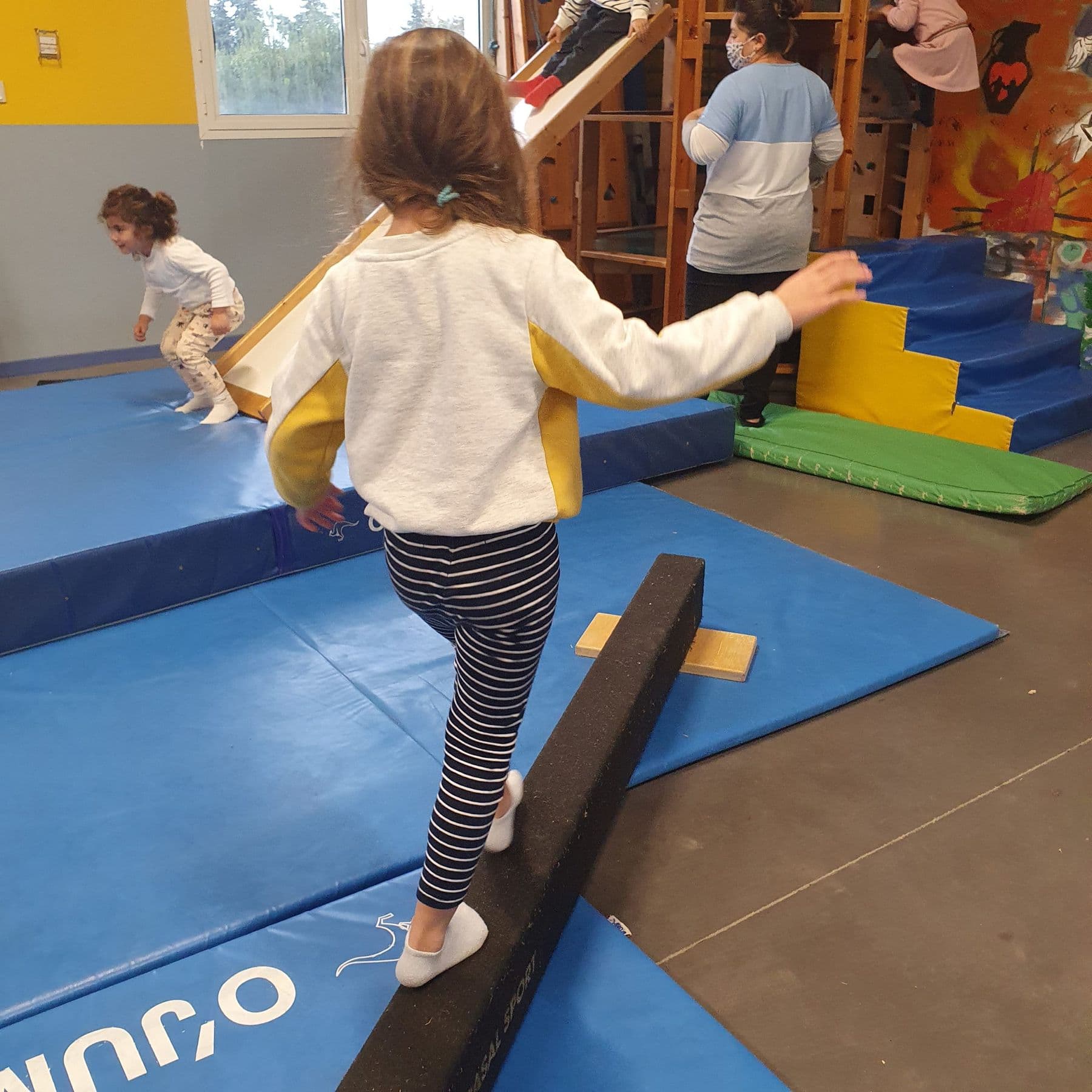 Un niño camina en equilibrio sobre una barra baja, en el gimnasio.