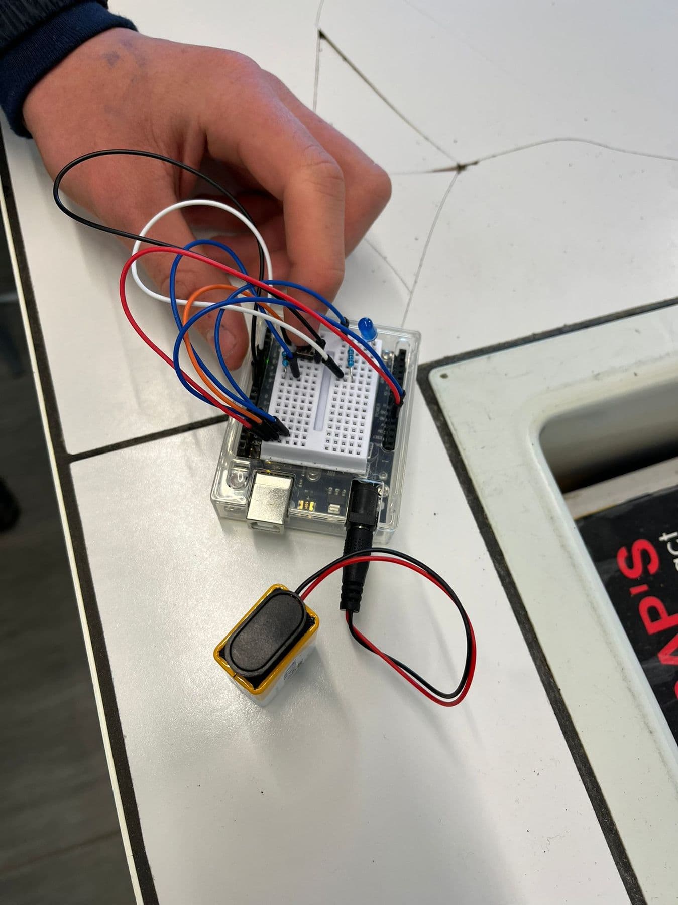 Des mains branchent des fils sur une carte électronique.