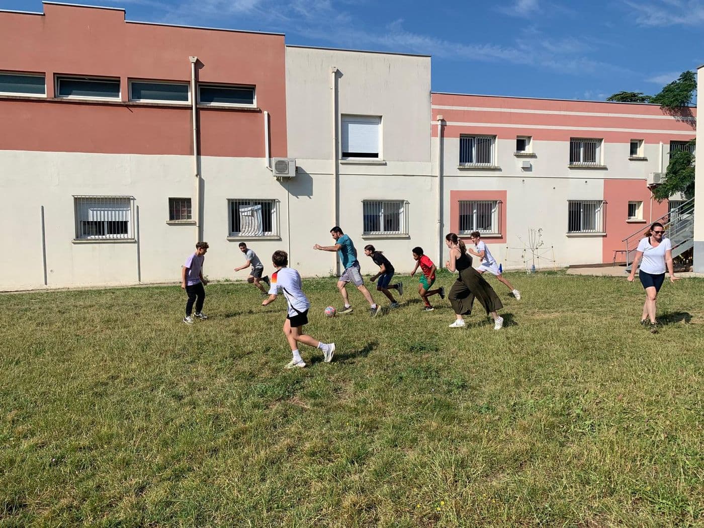 Partie de football sur la pelouse, devant les bâtiments de l'école.