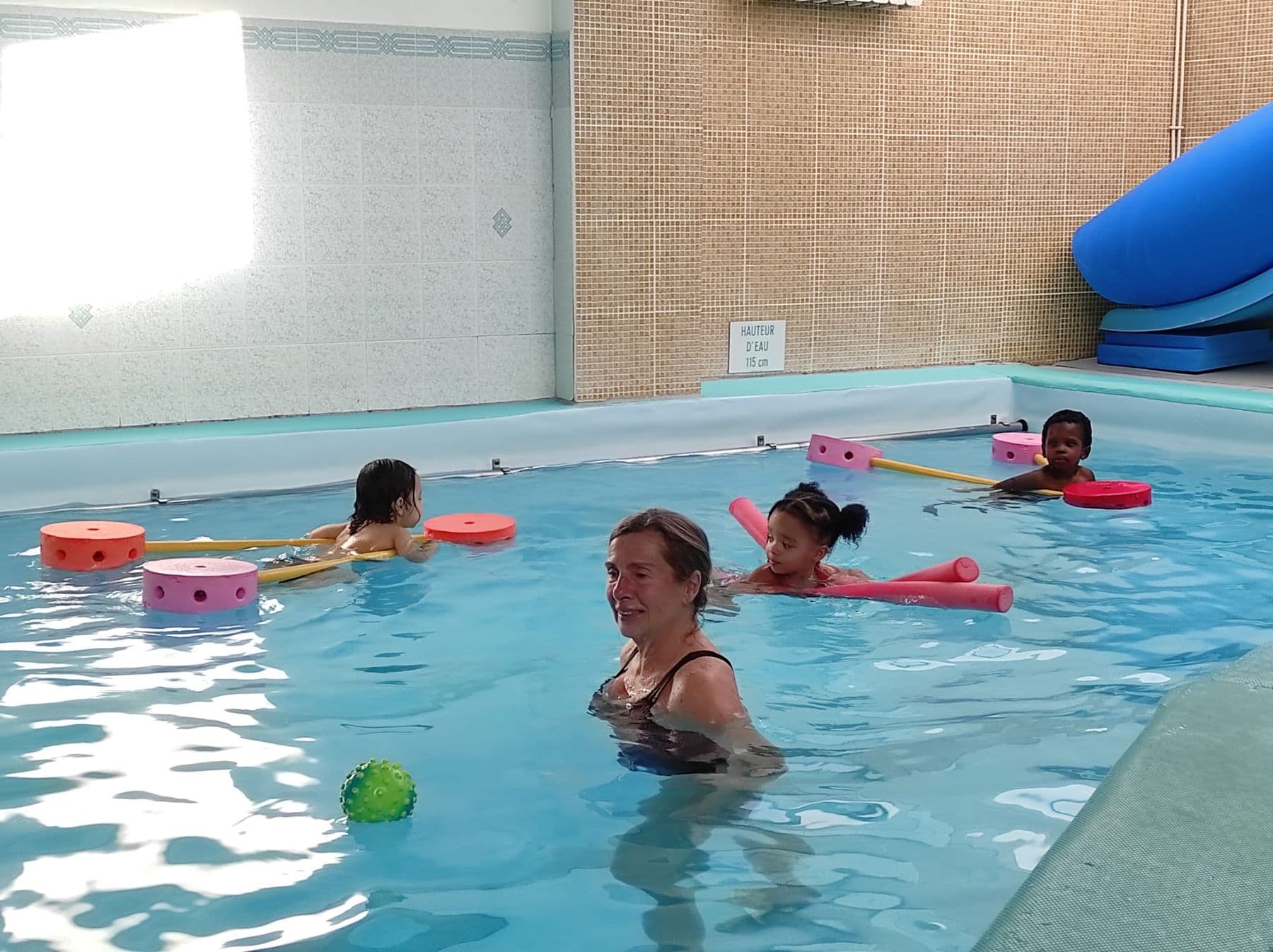 Les enfants de Toute Petite Section dans la piscine, encadrés par une adulte.