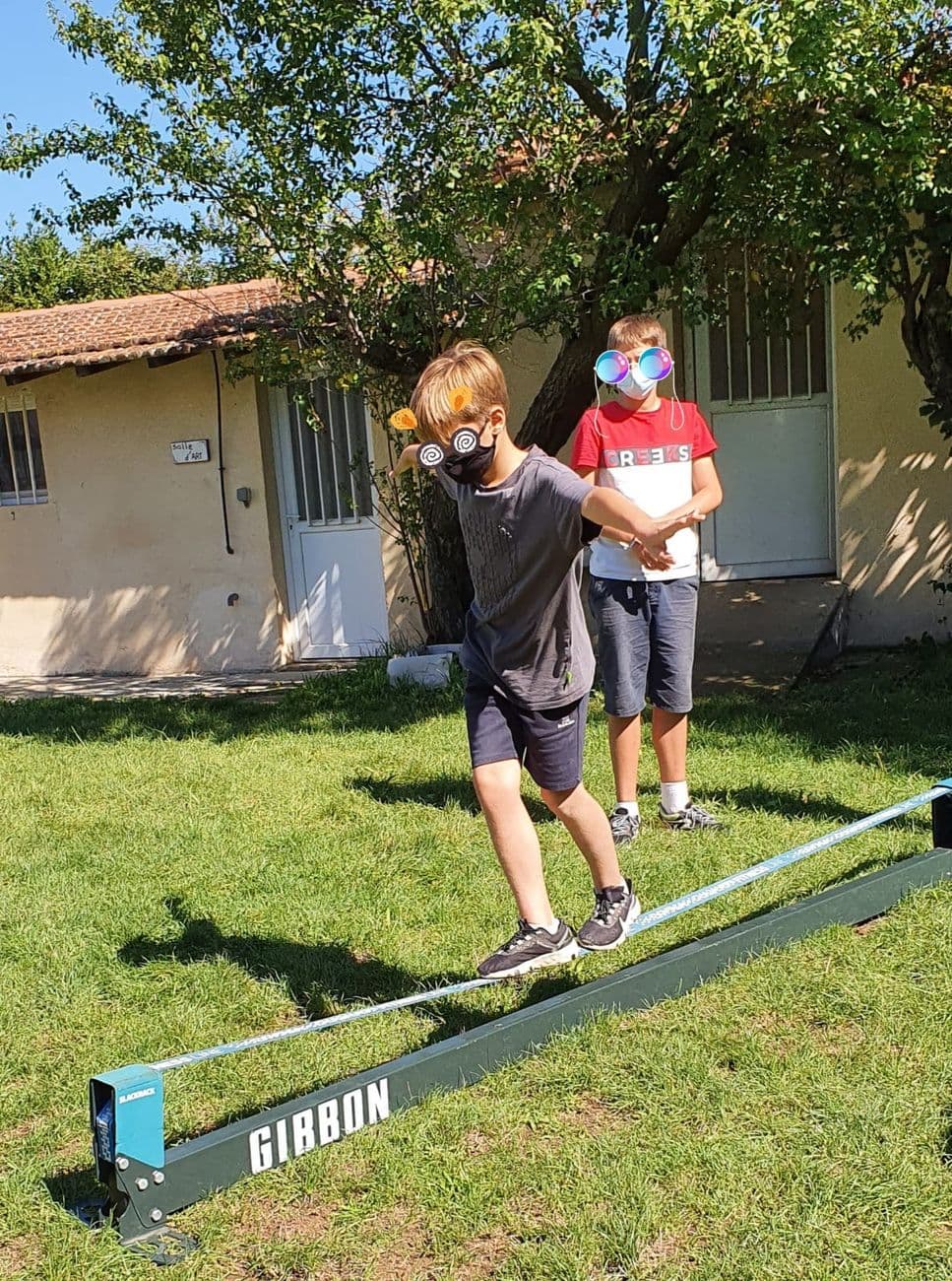 Deux élèves s'essaient à la slackline sur la pelouse.