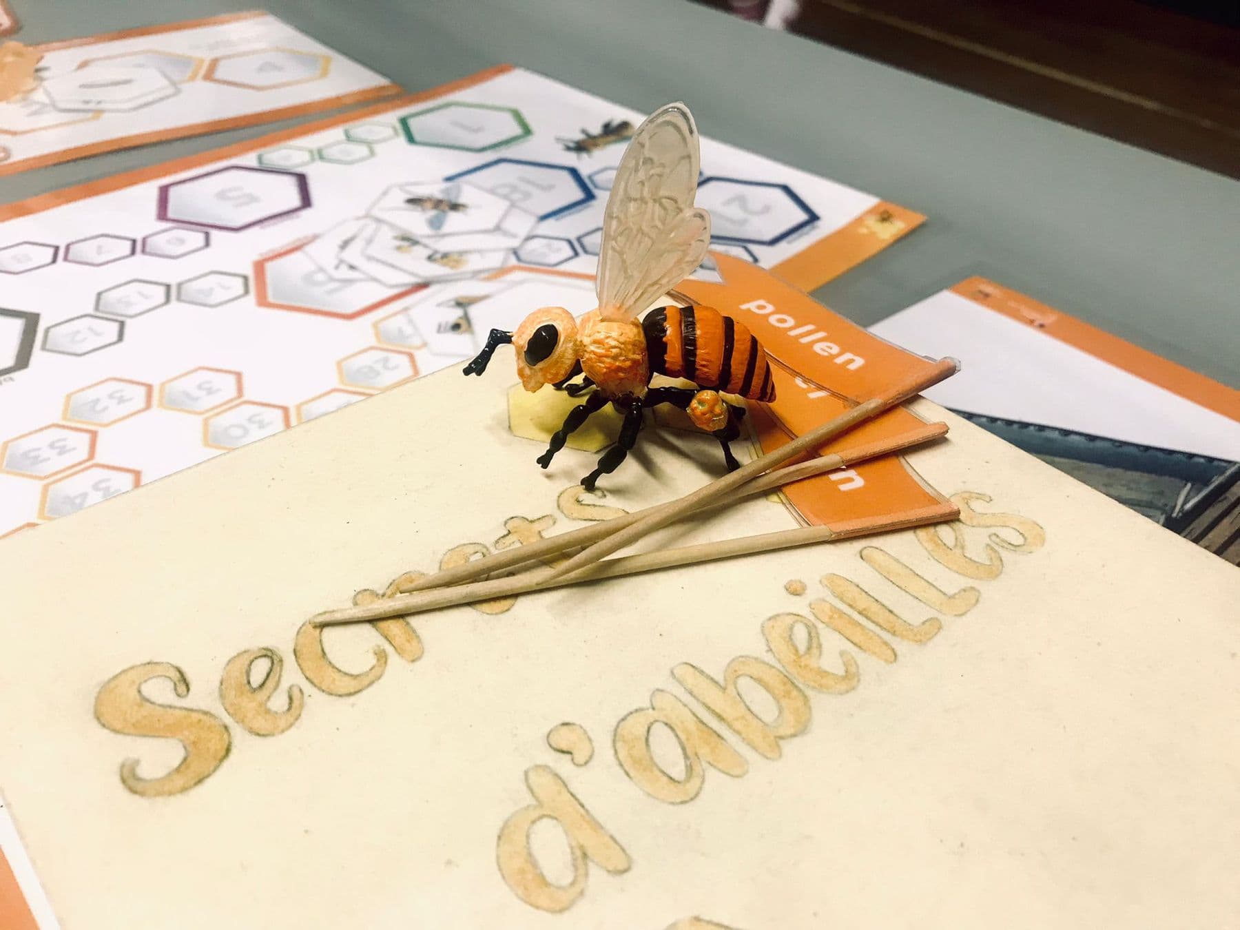 Une maquette d'abeille posée sur un jeu pédagogique consacré aux abeilles.